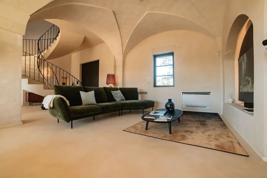 Minimalistischer Wohnraum in einem restaurierten Steingebäude mit Gewölbedecke, Wendeltreppe und zeitgenössischen Möbeln