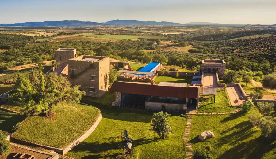 Luftaufnahme eines restaurierten historischen Steinanwesens mit Pool, umgeben von Olivenhainen und sanfter Hügellandschaft im warmen Sonnenlicht